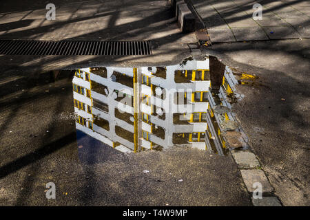 Social housing reflected in a puddle at Kottbusser Tor in Berlin, Germany. Stock Photo