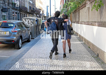 Young couple rear back view walking together along Rua de Cedofeita pavement sidewalk after work in spring Porto Portugal Europe EU  KATHY DEWITT Stock Photo