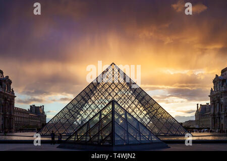 Clearing rainstorm over the iconic glass pyramid in the courtyard of Musee du Louvre, Paris, France