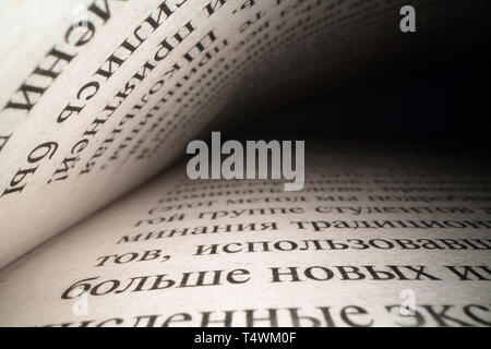 Inside the book concept. Cyrillic letters and words on an open book with black dramatic background. Education, knowledge concept, russian letters Stock Photo