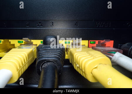 Multicoloured network cables inserted in the router panel on a dark background. Internet connection, communication industry Stock Photo