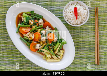 Thai stir fried vegetables and mushrooms in oyster sauce, Served with rice. Wooden chopsticks on the side. Top view. Stock Photo