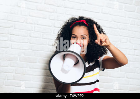 Portrait of happy african american woman shouting with megaphone for promotion, advertising. Black girl smiling and laughing for fun, joy, happiness Stock Photo