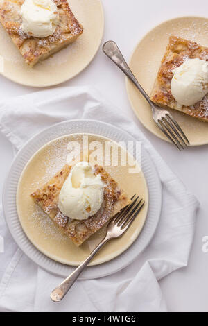 Three plates containing apple cake and vanilla ice cream on a white surface Stock Photo