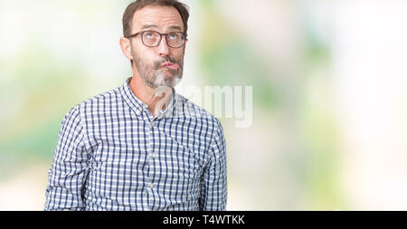 Handsome middle age elegant senior business man wearing glasses over isolated background making fish face with lips, crazy and comical gesture. Funny  Stock Photo