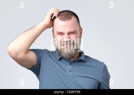 Confused man with beard scratching head looking at camera Stock Photo