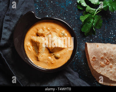 Indian food paneer butter masala in black bowl on dark background. Shahi paneer butter masala or cheese cottage curry top view. Shahi paneer is popular indian lunch or dinner meal. Copy space for text Stock Photo