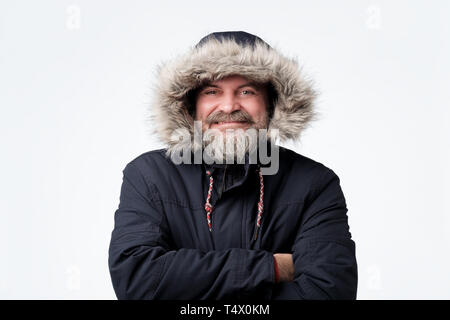 Handsome mature man wearing warm winter parka and hood, smiling Stock Photo