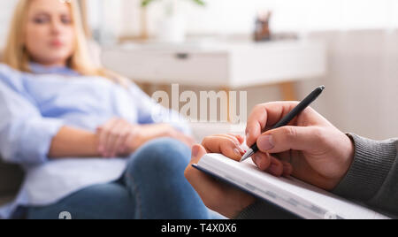 Professional psychotherapist taking notes, listening to patient Stock Photo