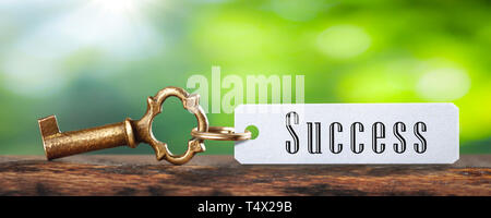 Old Brass Key And Tag With The Word Success On Wooden Table With Green Background - Business / Financial Success Concept Stock Photo