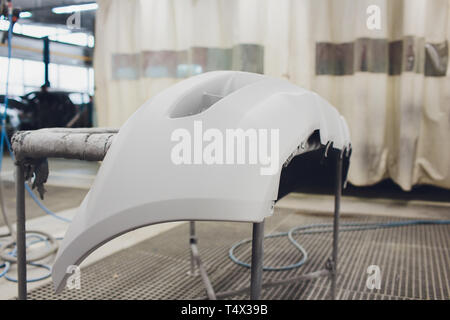 Repair of the rear bumper of a white car after an accident with the help of multi-colored putty in a workshop for painting vehicles in special chamber Stock Photo