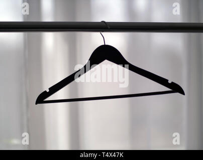 Clothes hanger on a metal rail against the window, close-up Stock Photo