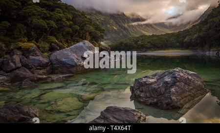 Early morning, horizontal landscape of Lake Mackenzie in early morning with boulders in foreground, treeline and mountain slopes in the background. Stock Photo