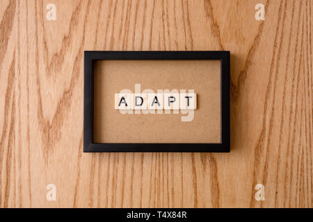 ADAPT word block on wood background. Stock Photo