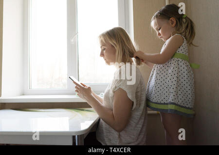 Mom and daughter are sitting by the window Stock Photo