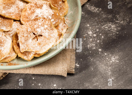 Part of round green plate with apple chips sprinkled with powdered sugar and cinnamon on burlap. Stock Photo