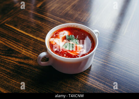 Christmas beetroot soup, borscht with small dumplings with mushroom filling in a ceramic bowl on a wooden table. Traditional Christmas eve dish in Pol Stock Photo