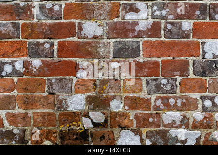 Close up an aging red and orange brick wall with crumbling mortar and bleached white spots Stock Photo