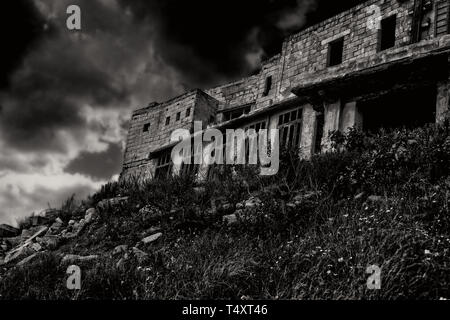 The Haunted House. An abandoned haunted house in black and white on a hill at night. Stock Photo