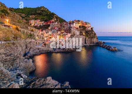 Sunset and night view of Manarola, one of the five Mediterranean villages in Cinque Terre, Italy, famous for its colorful houses and harbor Stock Photo