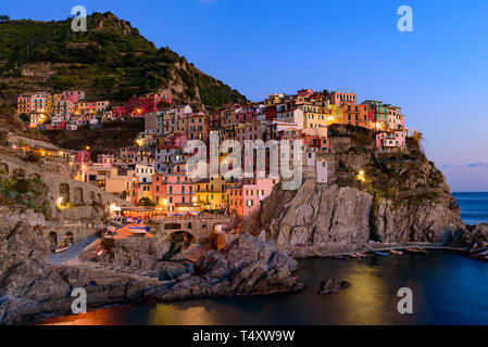Sunset and night view of Manarola, one of the five Mediterranean villages in Cinque Terre, Italy, famous for its colorful houses and harbor Stock Photo