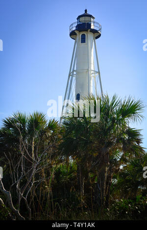 Palm trees and coastal grasses surround the Victorian lighthouse known as the Gasparilla Island Lighthouse on Boca Grande, FL Stock Photo