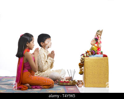 YOUNG INDIAN BOY AND GIRL performing puja TO LORD GANAPATI Stock Photo