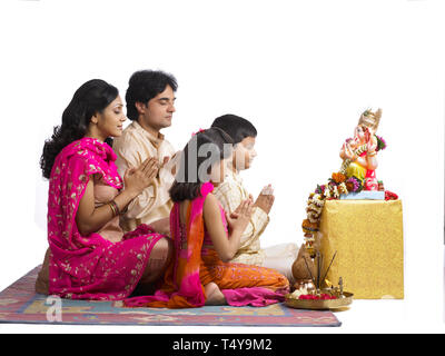 INDIAN FAMILY OF 4 performing puja TO LORD GANAPATI Stock Photo