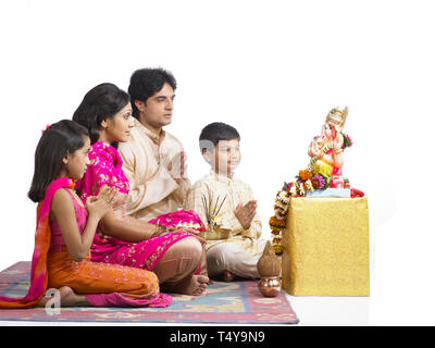 INDIAN FAMILY OF 4 performing puja TO LORD GANAPATI Stock Photo