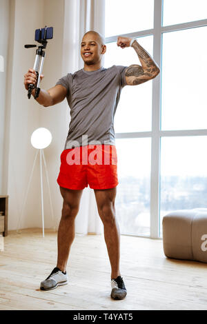 Athletic man wearing red shorts making selfie showing his biceps Stock Photo