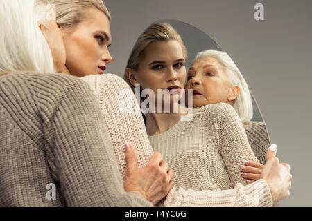Serious aged woman standing behind the young one Stock Photo