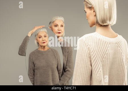 Nice aged woman holding an oval mirror Stock Photo