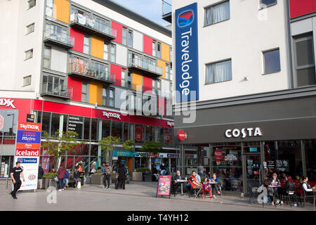 Customers of Costa Coffee consume drinks outdoors in the sunshine in a modern shopping and housing development, Wembley Central Stock Photo