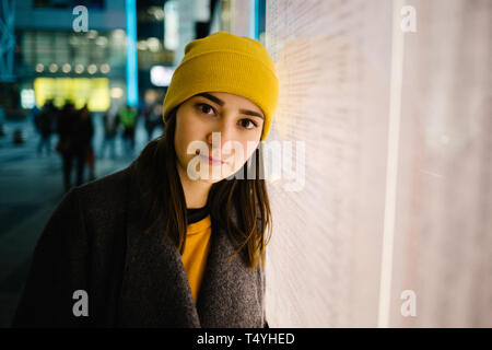 Young woman leans at a illuminated departure plan. Travel,lifestyle and youth concept. Stock Photo