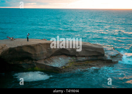 miniature man and drum set on a cliff in the middle of the ocean Stock Photo