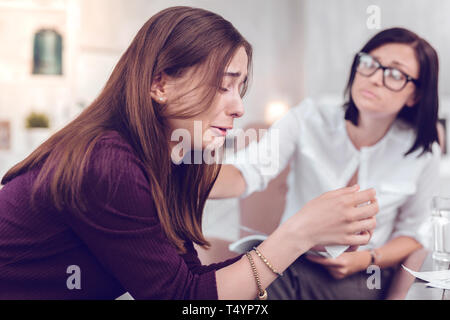 A dark-haired charming counselor comforting crying emotional dark-haired young woman Stock Photo