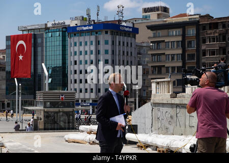Istanbul, Turkey - June 17, 2016: News reporter reporting in front a camera for a live telecast at Taksim square in Istanbul. Stock Photo