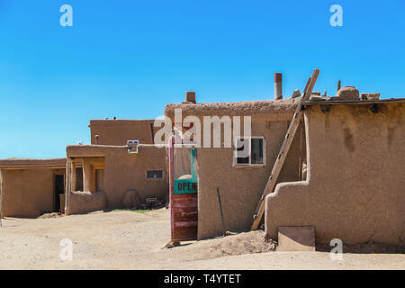 Side view of adobe mud buildings in a pueblo in the Southwestern USA, with shops with doors open for selling local crafts and foods to tourists Stock Photo
