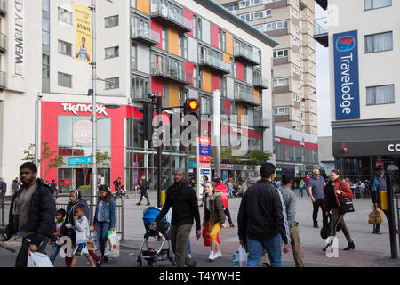Pedestrians crossing High Road, Wembley, in front of a modern shopping and housing development at Wembley Central. Stock Photo
