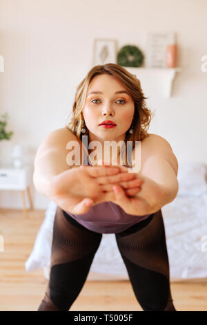 Useful exercises. Attractive young woman leaning forward while having a workout at home Stock Photo