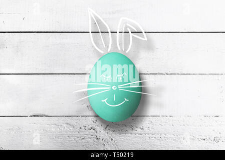 easter bunny face drawn on easter egg against white rustic wooden table happy easter concept Stock Photo