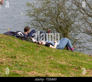 Young couple in a park relaxing in the sunshine by the sea. Stock Photo