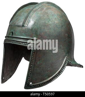 An Illyrian helmet, 6th century BC. Bronze with dark green patina. Tall skull with distinctly raised and stepped ridges, fastening hooks for the attachment of a crest at front and at back. Large face-opening surmounted by two ribs across the brow, long pierced cheek-pieces and flared neck-guard. A row of lenticular decorative pins around the perimeter. Partially with more extensive replacements and restorations at the crown, the face-opening and the nape. Height 23 cm, weight 1002 g. Provenance: German private collection, 1970s. historic, histori, Additional-Rights-Clearance-Info-Not-Available Stock Photo