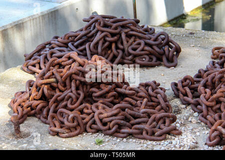 Rusty metal chain lies on the concrete in the port Stock Photo
