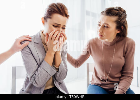 woman consoling another crying woman during therapy meeting Stock Photo