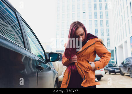 Pretty young woman standing and looking keys of car in her bag outdoors. Stock Photo