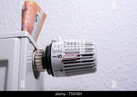 Thermostat on a radiator with banknotes - save heating costs Stock Photo