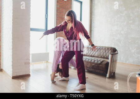 Concept pajama party. Girlfriends of sister fight pillows on bed ...