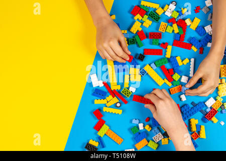 Children hands play with colorful Lego blocks on the table Stock Photo