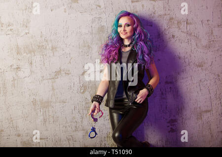 Daring rebel rocker, in black leather clothes with colored hair. Young stylish woman with trendy gradient toning hair, purple and blue. Stock Photo
